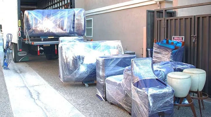 Furniture wrapped in stretch film next to a moving truck